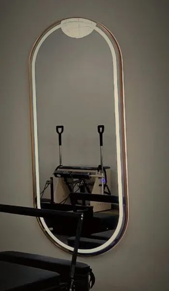 A gold-rimmed oval mirror, lit from within