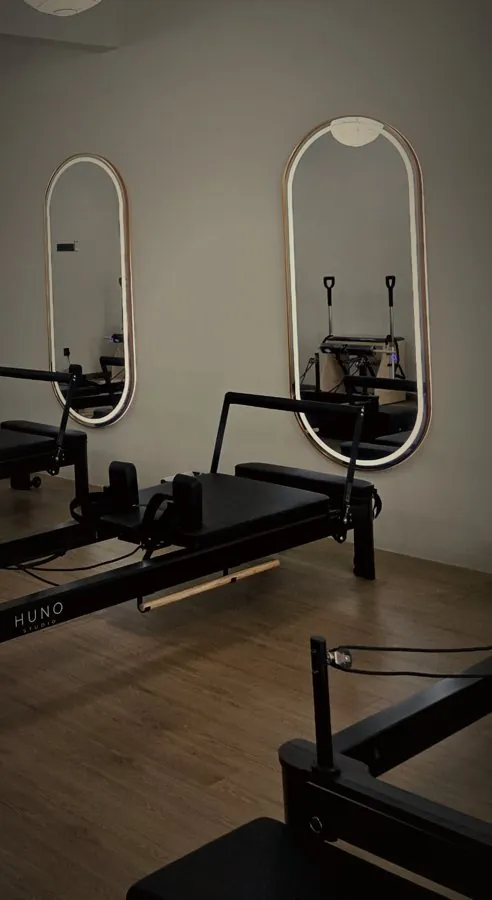 Lit oval mirrors above a black reformer